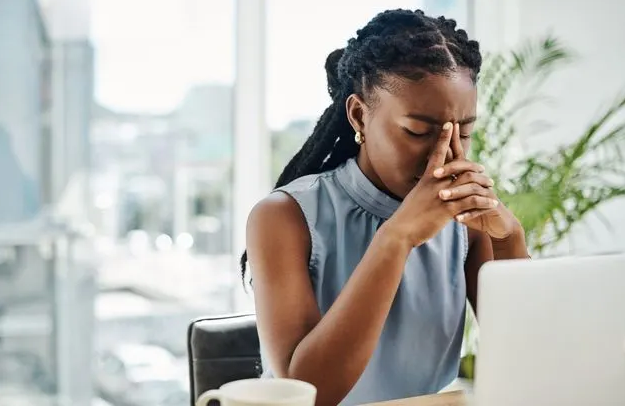 A Black professional woman pauses during work, reflecting the growing economic pressures and instability many face in today’s shifting labor market. (Photo: Delmaine Donson via Getty Images)