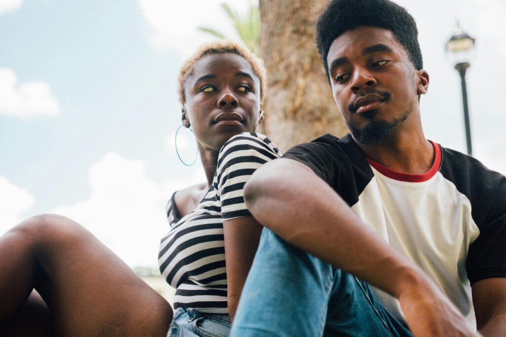 Young man and woman sitting outdoors together under a blue sky